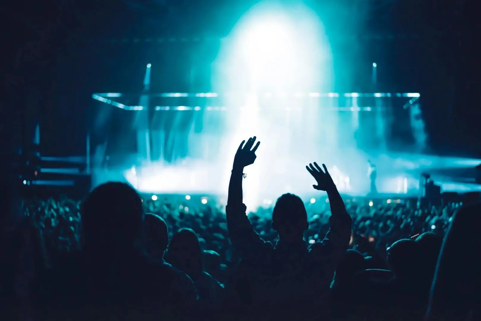 Público com as mãos para cima em frente ao palco iluminado