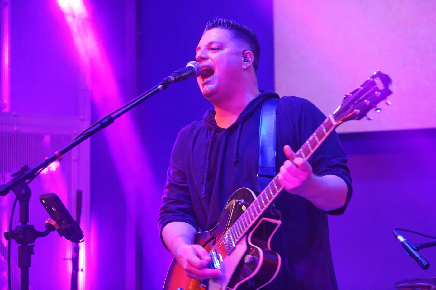 Tiago Adorno cantando e tocando guitarra com luz roxa